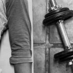 person in black pants and black socks holding dumbbell